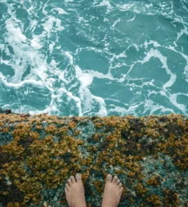 Bare feet at the edge of turquoise ocean water