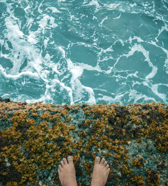 Bare feet at the edge of turquoise ocean water